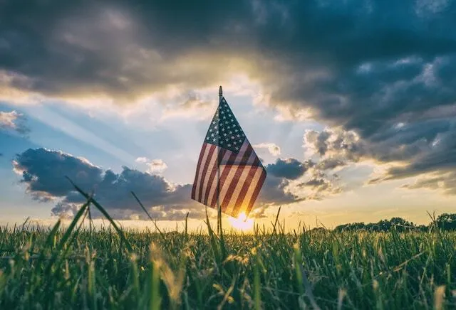 United States flag standing in a field during sunset